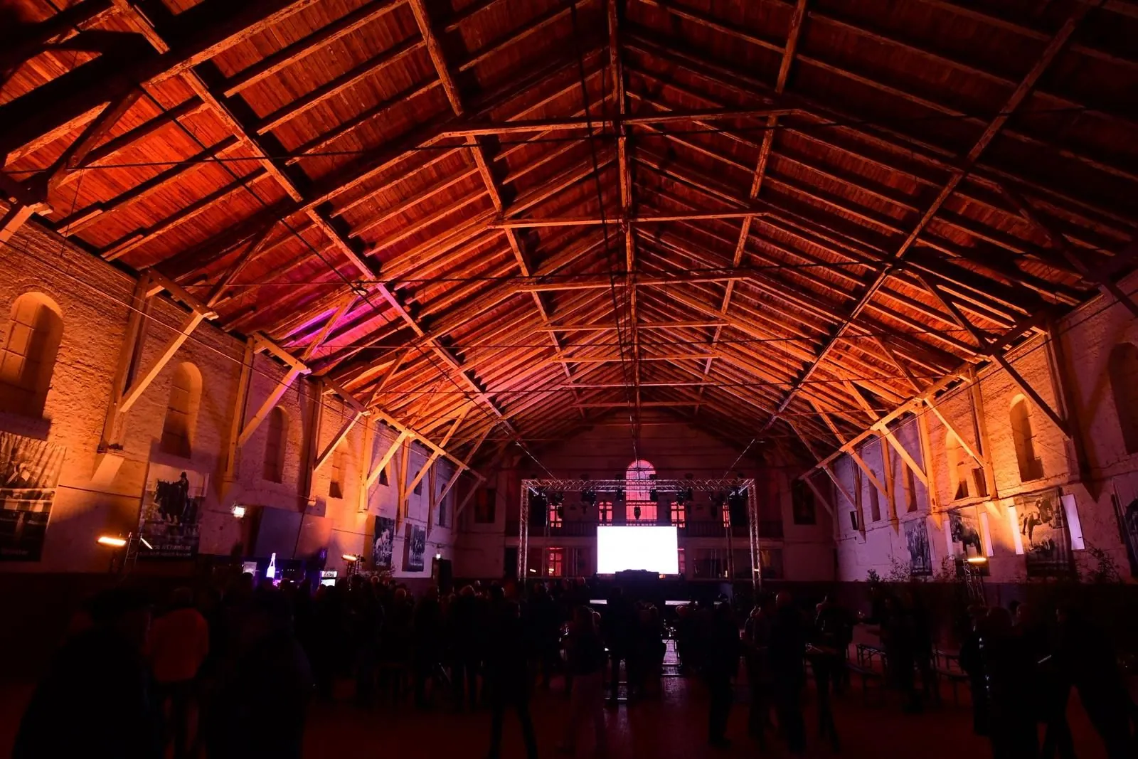 Abiball in einer großen, warm ausgeleuchteten Halle bei Nacht – Gäste an festlich gedeckten Tischen unter offenem Holzdachstuhl